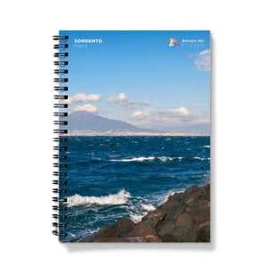 a spiral notebook with a photo of the ocean and a mountain in the background