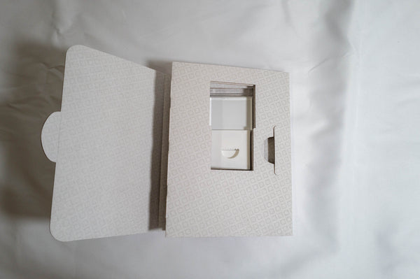 a white box with a cutout, possibly containing a small object or a compartment, placed on a white surface.