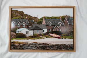 a picturesque coastal village with quaint cottages and a red boat resting on the sandy beach.
