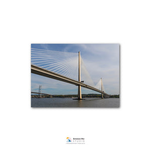A large suspension bridge spanning across a body of water, with its cables and towers visible against a blue sky with some clouds.