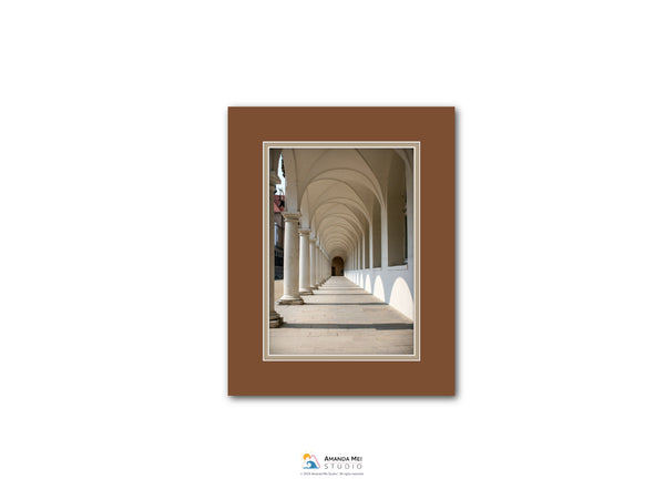 a long, arched hallway with white columns lining the sides, creating a sense of depth and perspective.