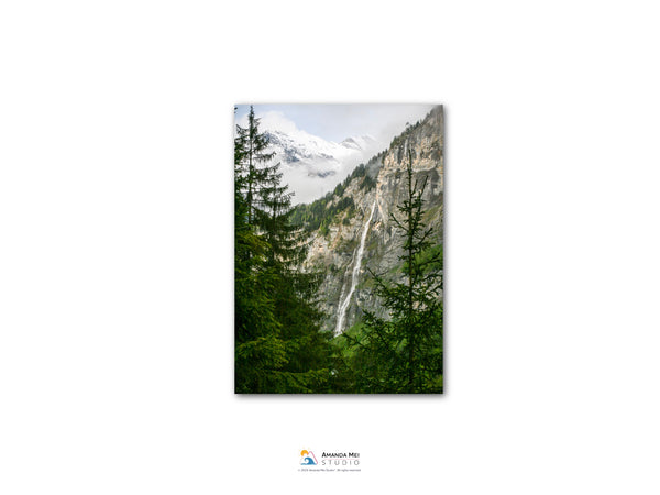 a majestic waterfall cascading down a rocky cliff surrounded by lush green trees.
