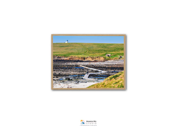 a scenic coastal landscape with a lighthouse on a hill, a rocky shoreline, and a small stream flowing through the area.