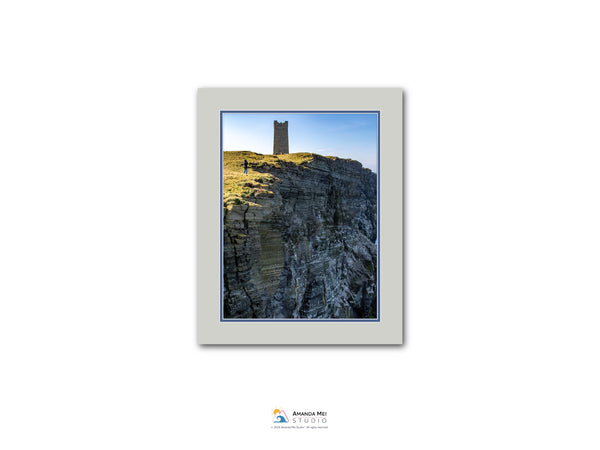a tall tower perched atop a rocky cliff, with a clear blue sky in the background.