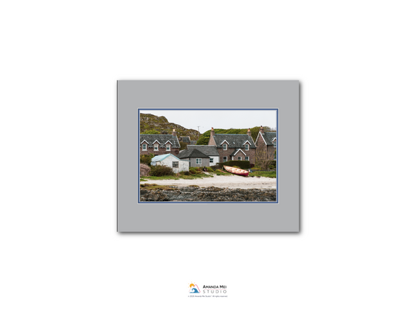 a coastal village with houses and boats on the shoreline.
