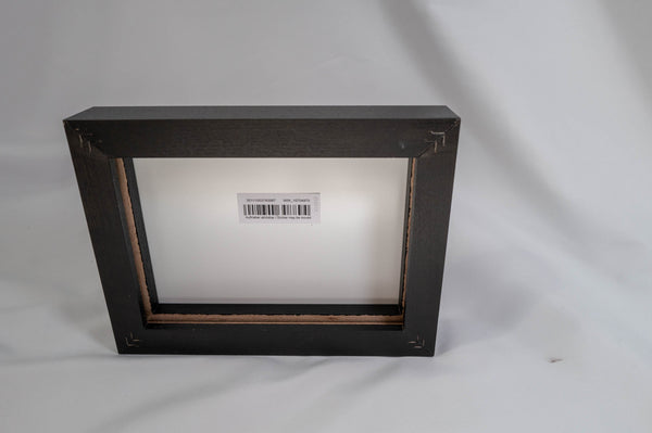 A black wooden frame with a white label inside, placed on a white background.