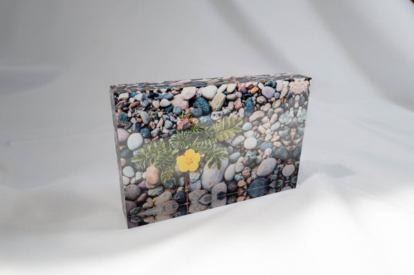 The image is a square-shaped object with a colorful, textured surface, featuring a variety of small rocks and pebbles in different colors and sizes.