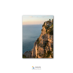 a cliff overlooking the ocean, with a small building perched on the edge.