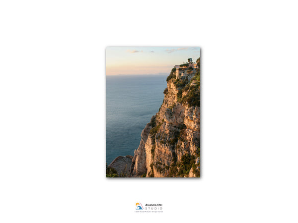 a cliff overlooking the ocean, with a small building perched on the edge.