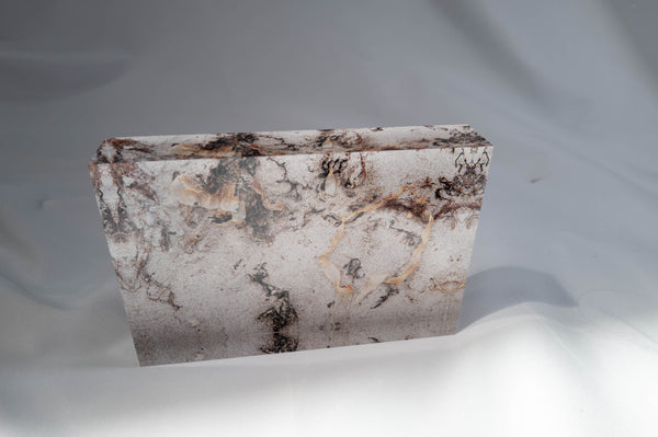 a square-shaped, textured surface with a pattern of black and brown swirls and lines, set against a white background.