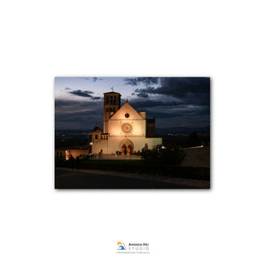 a large, white church with a bell tower, illuminated at night against a dark sky.