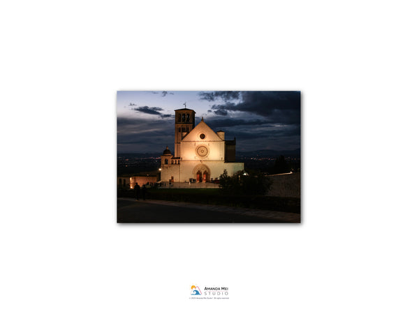 a large, white church with a bell tower, illuminated at night against a dark sky.