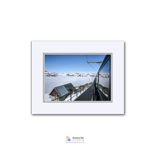 A snowy mountain landscape with a ski lift and a building in the distance, captured from a high vantage point.
