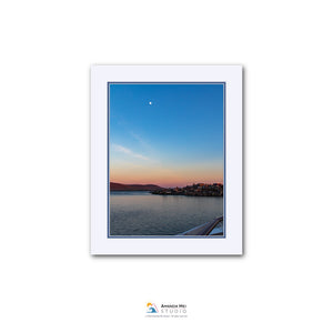 a serene sunset over a body of water, with a small town or village visible in the distance.